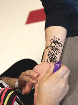 Sarah Muhsen draws a henna tattoo on her sister, Hind Muhsen, 19, a general transfer student.