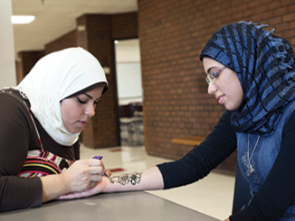Sarah Muhsen draws a henna tattoo on her sister, Hind Muhsen, 19, a general transfer student. (Photos by Quyen Huynh)