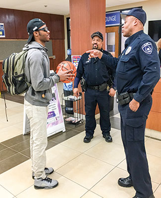 Forest Park police officers James Kenner, right, and Dan Taylor chat with accounting major Cornelius Burch after the officers replaced a basketball stolen from Burch at the YMCA. (Photo by Destini Clark)