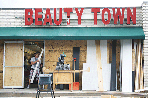 A construction worker repairs damage caused by looters at a beauty supply store in Ferguson. (Photo by Evan Sandel)
