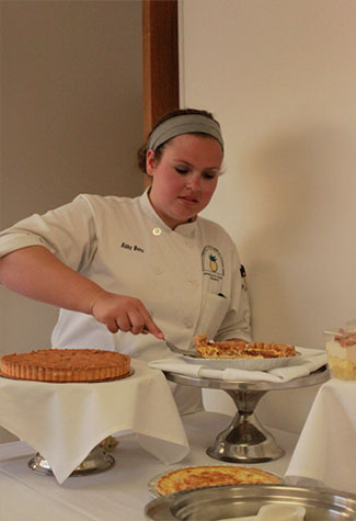 Abby Benz, 20, vice president of the Cuisine Club, serves quiche. (Photo by Quyen Huynh)