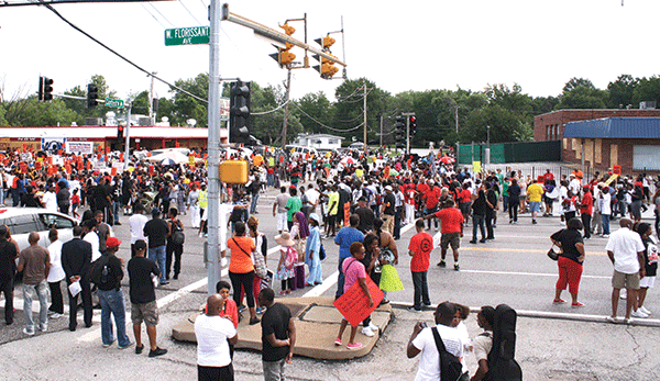 Protestors fill the intersection outside a burned QuikTrip at Florissant and Canfield in Ferguson. (Photo by Evan Sandel)