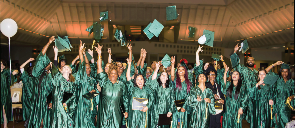  Graduates of the HiSET FastTrack Program hurl their mortar board caps skyward after the graduation ceremony in the Forest Park cafeteria. (Photo Sara Schmidt)