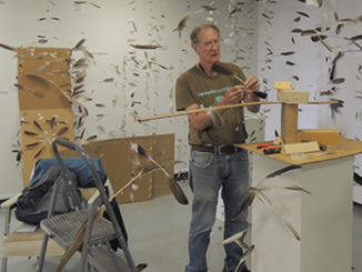 Artist Don Wilson hangs feathers on fishing line while installing his exhibit, “O’ to Fly Again,” which opens July 1 in the Gallery of Contemporary Art at Forest Park. (Photos by Yuanyuan Ji)