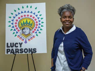 Tamela Turner poses next to a poster of Lucy Parsons, a labor organizer, radical socialist and anarchist communist. (Photo by Daniel Shular)