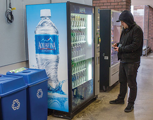Photography student Dane McCrary, 30, buys a drink from the vending machine on the fourth floor of F Tower on Dec. 4. (Photo by Daniel Shular)