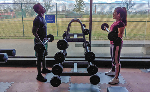 Pre-med major Nicodemus Uringi, 18, left, and nursing major Deena Ghaley, 22, lift barbells in the weight room, which is part of the Forest Park fitness center. (Photo by Neftali Acosta)