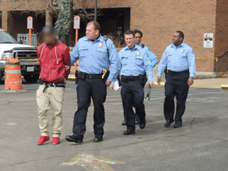 Campus police officers lead away a student who was believed to have a firearm, but was later released by the St. Louis Metro Police Department. His face is blured to protect his identity. (Photo by Markeith Childress)