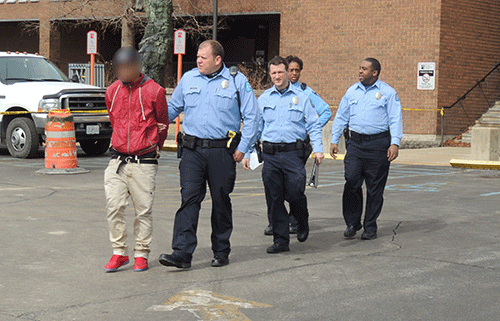 Campus police officers lead away a student who was believed to have a firearm, but was later released by the St. Louis Metro Police Department. His face is blured to protect his identity. (Photo by Markeith Childress)