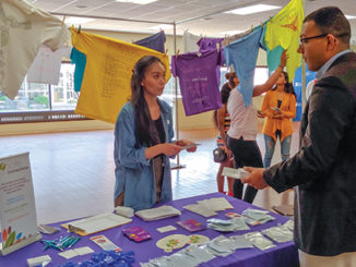 Cindy Punzalan, crisis and community outreach coordinator from Safe Connections, speaks with social work major Koshua Blash, 20, at The Clothesline Project display. (Photo by Neftali Acosta)