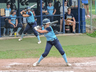 STLCC’s Miranda Hudson eyes a pitch in the Region 16 championship game against Mineral Area College at Meramec. Chloe Johnson takes her batting stance while on deck. Coach Kristi Swiderski, at right in the dugout, observes the action. (Photo by Timothy Bold)