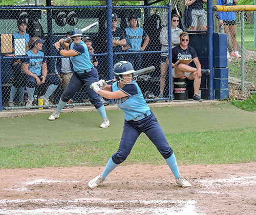 STLCC’s Miranda Hudson eyes a pitch in the Region 16 championship game against Mineral Area College at Meramec. Chloe Johnson takes her batting stance while on deck. Coach Kristi Swiderski, at right in the dugout, observes the action.  (Photo by Timothy Bold)