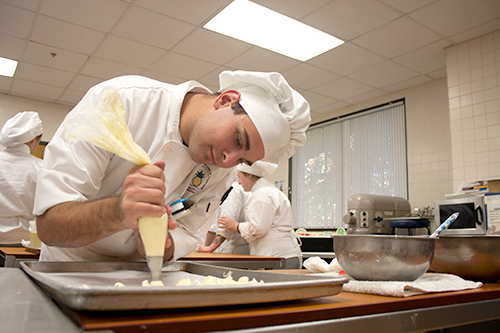 David Stuckel practices garnishing skills with a tube of icing. (Photo by Evan Sandel)