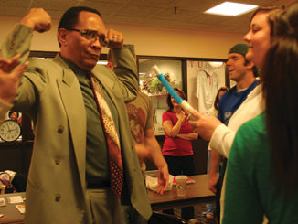 Forest Park President Morris F. Johnson III flexes his muscles after blowing into a machine that measures lung capacity on Respiratory Therapy Day in the Student Center lobby in 2009. (Photo by Tania Hammond)