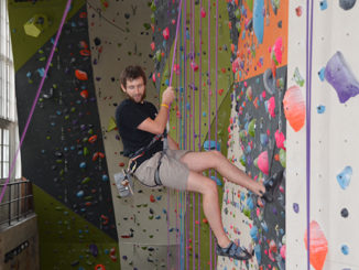 General transfer student Jake Leech, 21, climbs the wall, above; Mark Applegate, below second to left, coaches some of his rock-climbing students. (Photo by Scott Allen)
