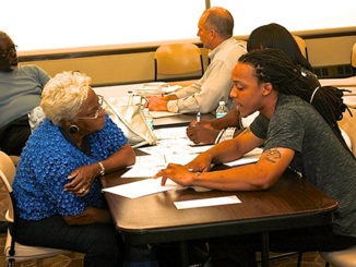 Navigator David Johnson of Grace Hill Health Center in St. Louis explains the new health-care law to a local resident in Cafe East. (Photo by Julian Hadley)