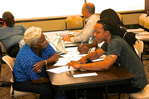 Navigator David Johnson of Grace Hill Health Center in St. Louis explains the new health-care law to a local resident in Cafe East. (Photo by Julian Hadley)