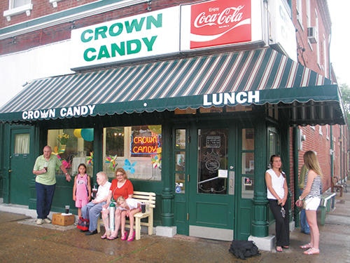 Customers take shelter from the rain under the awning at Crown Candy Kitchen, which sits at the intersection of St. Louis Avenue and 14th Street. (Photo by Jamie Greene)