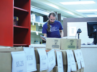 Forest Park graduate Kristopher Claywell, 37, sorts books in the relocated bookstore. (Photo by Garrieth Crockett)