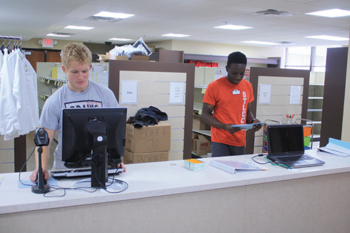 Employee Nate Heagney, 19, learns the bookstore’s computer system while Jonathan Edwards, 22, works nearby. (Photo by Garrieth Crockett)
