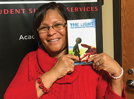Debra Hutcherson shows off a copy of her self-published book, “The Light that Brought Me Through.” She will sign copies this week in the Highlander Lounge. (Photo by Ethan Tutor)