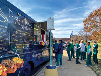 Students line up for lunch at the Doggie Mac’s food truck, which was parked along College Drive south of the “Light Walls” sculpture. (Photo by Leilani England)